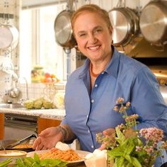 a woman standing in front of a plate of food on a kitchen counter with pots and pans behind her