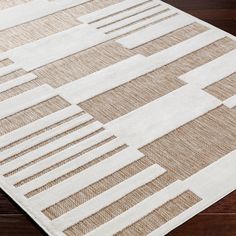 a beige and white area rug on a wooden floor