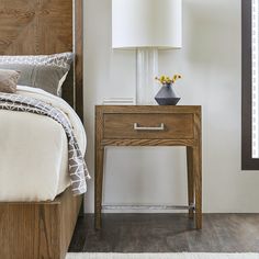 a bedroom with a bed, night stand and lamp on the nightstand next to it