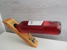 a bottle of wine sitting on top of a wooden stand next to a white wall