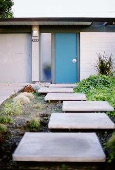 there is a blue door and some steps in front of the house that are made out of concrete