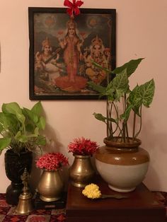 there are many potted plants on the table in front of this painting and other decorations