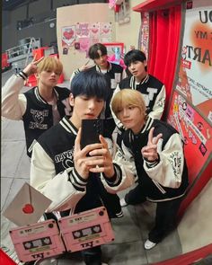 group of young men standing in front of a mirror taking a selfie with their cell phones