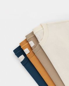 four different colors of t - shirts on a white background, one is blue, the other is brown