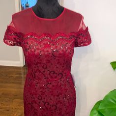 a red dress with sequins on it sitting on a mannequin