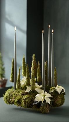 a moss covered table with candles and flowers