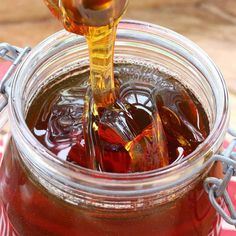 a jar filled with liquid sitting on top of a red and white checkered table cloth