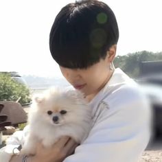 a woman holding a small white dog in her arms