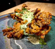 a blue plate topped with fried food on top of a wooden table