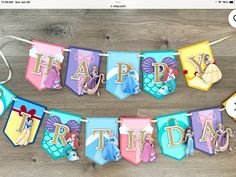 a birthday banner that says happy birthday with princesses and mermaids hanging from it