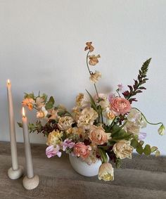 two candles are sitting next to a vase with flowers in it and one candle is lit