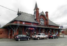 two cars parked in front of a red brick building with a clock tower on top