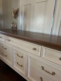 a white dresser with wooden top and drawers