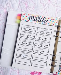 a planner is open on top of a quilted surface with the word march written in it