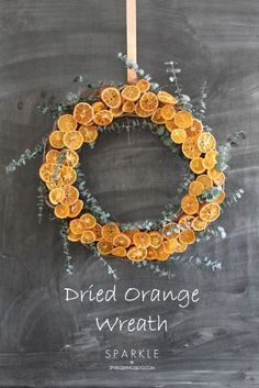 an orange wreath hanging on a chalkboard with the words dried orange wreath written below it