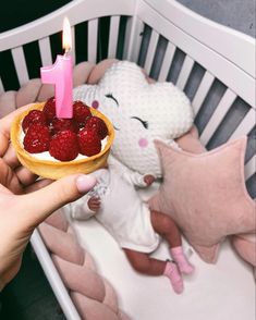 a person holding a small bowl with strawberries in it and a pink candle on top