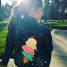 a woman sitting on a bench wearing a denim jacket with an ice cream cone design