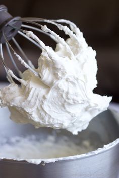 a metal bowl filled with whipped cream and a whisk