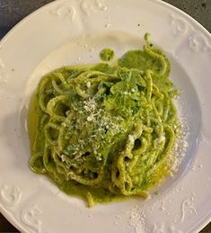 a white plate topped with pasta covered in pesto