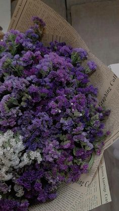 purple and white flowers sitting on top of newspaper