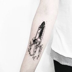 a small black and white rocket tattoo on the arm