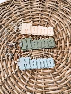 three key chains sitting on top of a wicker basket with the word mama spelled out