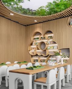 a dining room with white chairs and wooden tables in front of a green tree mural