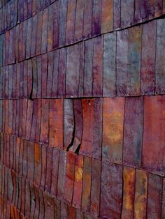 a brick wall that has been painted red and purple with some rust on it,