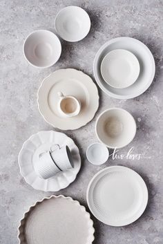 an assortment of white plates and bowls on a gray surface with text overlaying the image