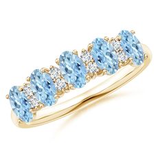 a yellow gold ring with blue topaz and white diamonds on the sides, in front of