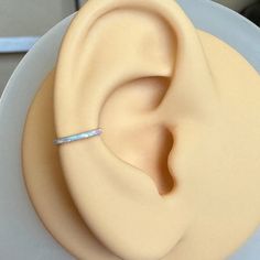 a close up of a fake ear on top of a white plate with a silver band