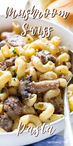 a white bowl filled with pasta and meat on top of a blue cloth next to a fork