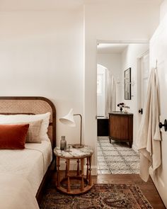 a bedroom with a bed, rug and lamp in it's corner next to a doorway