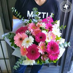 a person holding a bouquet of flowers in front of a door with the words m & t on it