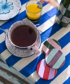 a cup of coffee sitting on top of a blue and white striped table cloth next to plates