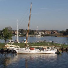 a sailboat sitting in the water next to a dock with other boats on it