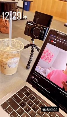 a laptop computer sitting on top of a table next to a cup of coffee and a camera