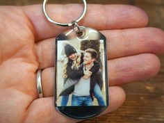 a person holding a keychain with a photo on it in the palm of their hand