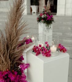 flowers and candles are sitting on the side of a white box with two vases