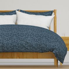 a bed with blue and white comforter on top of it next to a wooden headboard