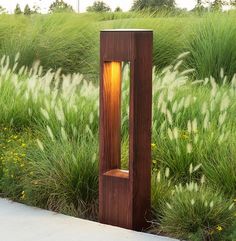 a tall wooden sculpture sitting in the middle of a field next to grass and flowers