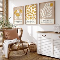 a white chair sitting next to a wooden dresser under three framed pictures on the wall