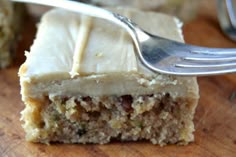 a close up of a piece of cake on a wooden surface with a fork in it