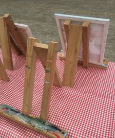 three easels sitting on top of a red and white checkered tablecloth covered ground