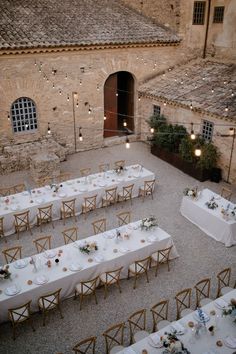 an outdoor venue with tables and chairs set up for a formal dinner in the courtyard