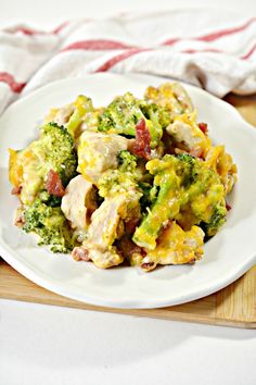 a white plate topped with broccoli and chicken covered in cheese on top of a wooden cutting board