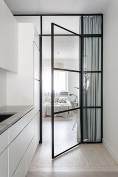 an open door leading to a bedroom with a bed in the background and white cabinets