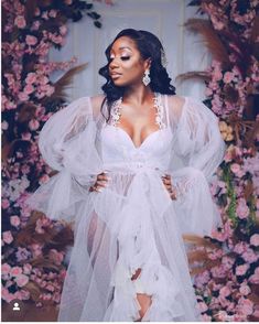 a woman standing in front of flowers wearing a white dress