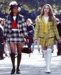 two women walking down the street in short skirts and plaid jackets with hats on their heads