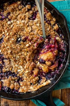 a skillet filled with blueberry crisp on top of a wooden table